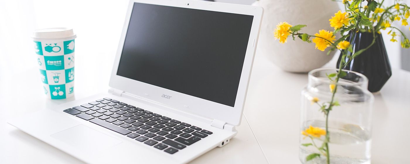 A clean desk with a laptop, notebook and coffee